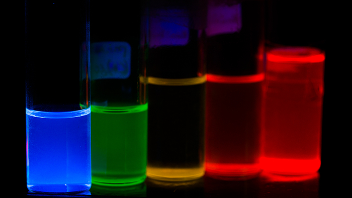 Fünf fluoreszierende Nanopartikelproben von blau (links) über grün, gelb, rot zu tiefrot (rechts)